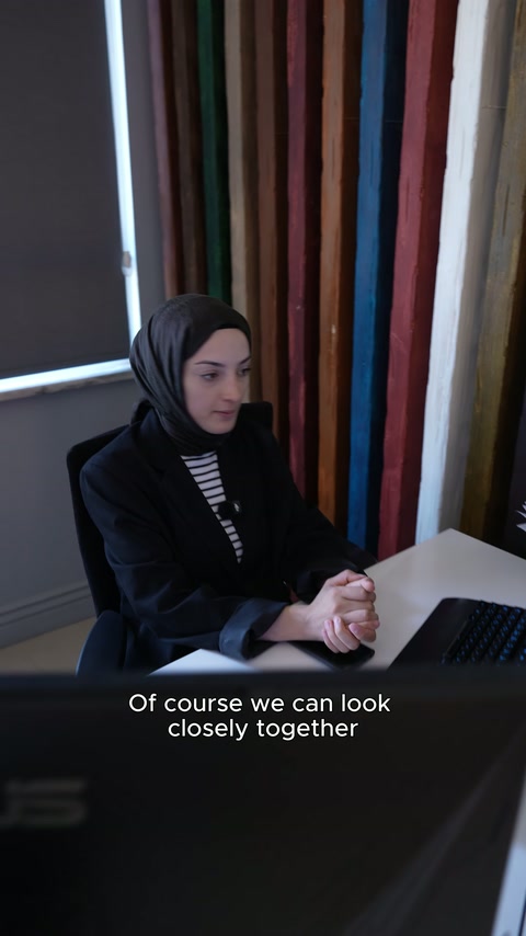 Kadın çalışan atölye üretimi hakkında bilgi verirken ellerini masada tutuyor