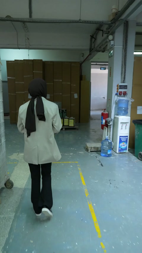 Çalışan, sarı çizgilerle ayrılmış fabrika geçiş yolunda ilerliyor