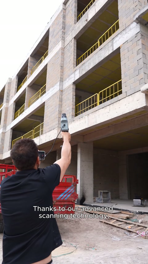 Operatör, elindeki tarayıcıyı kaba inşaat cephesine doğru tutuyor.
