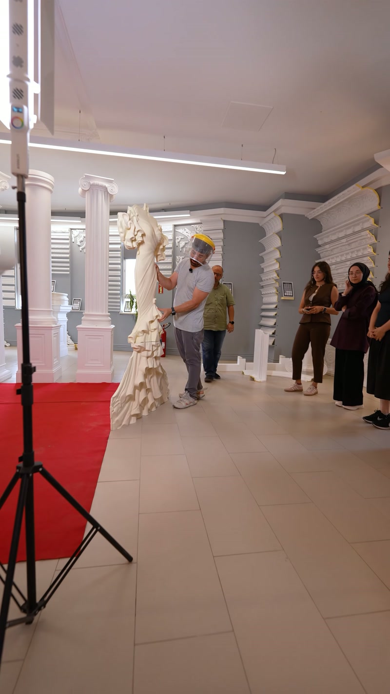 Ziyaretçiler, sütunlarla çevrili salonda dekoratif rölyef tasarımını inceliyor.