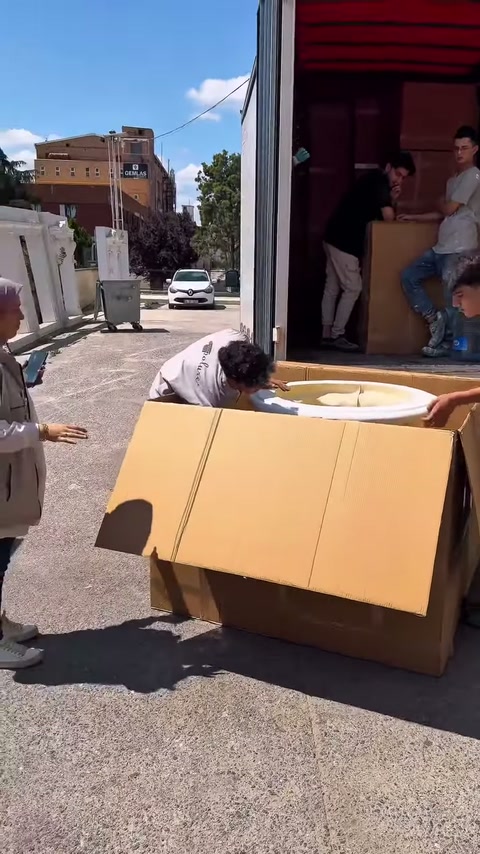 Kutunun yanında eğilen çalışanlar ürünün alt kenarlarına uzanıyor