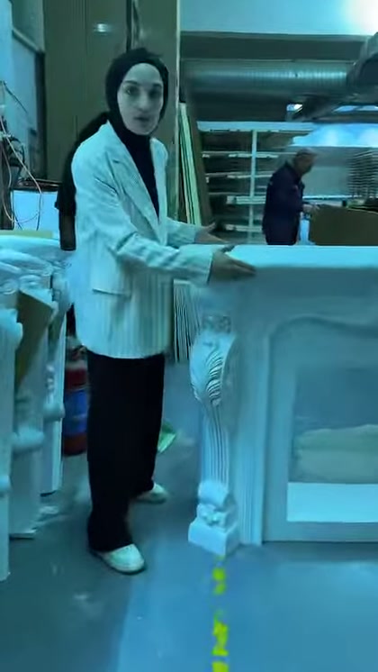 Kabartmalı köşe detayına sahip hazır şömine sunucunun yanında duruyor
