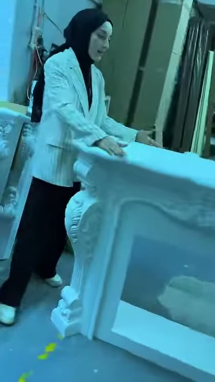 Sunucu dekoratif şöminenin üst yüzeyine dokunarak yapısını tanıtıyor