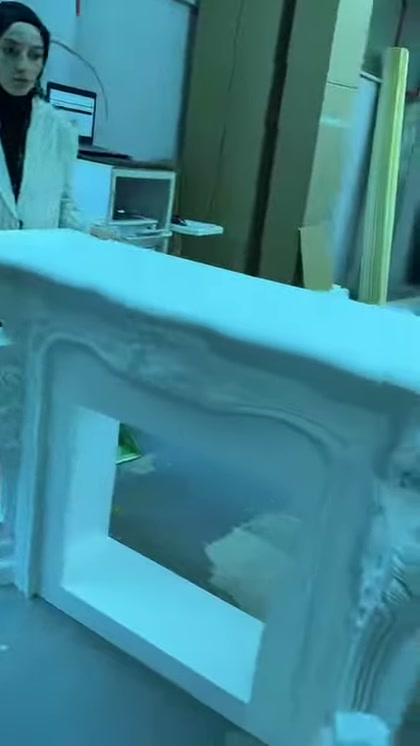 Yakın planda şöminenin düz çerçevesi ile köşe süslemesi gösteriliyor