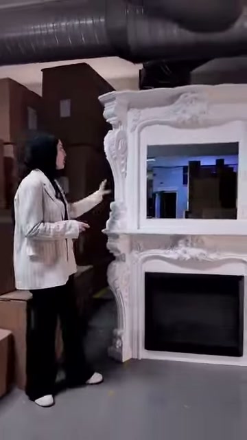 Beyaz şömine modelinin oyma görünümlü yan detayları öne çıkıyor
