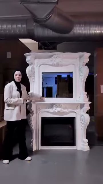 Sunucu yüksek beyaz şömine modelini depo ortamında önden sunuyor