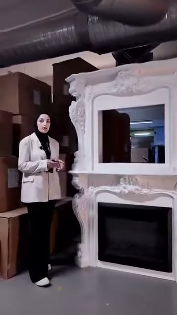 Sunucu elektrikli hazneli beyaz şömine çerçevesinin yanında duruyor