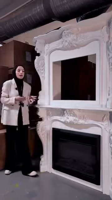 Klasik biçimli beyaz şömine, depo içindeki teşhir alanında duruyor