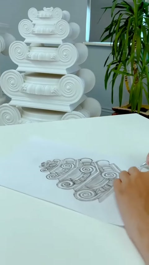 Çalışma masasında eskiz sürerken beyaz başlık modelleri arkada duruyor.