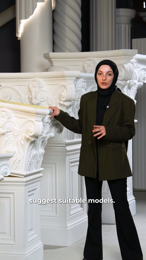 Sunucu, yanındaki geniş volütlü sütun başlığına avucuyla yöneliyor.
