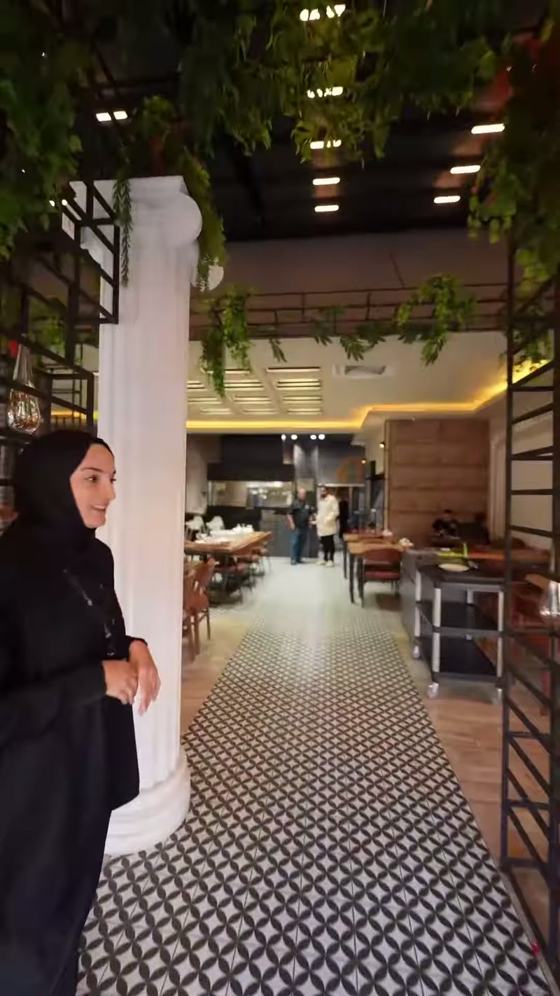 Restoran salonunun girişinde beyaz yivli sütun ve İyon başlık seçiliyor.