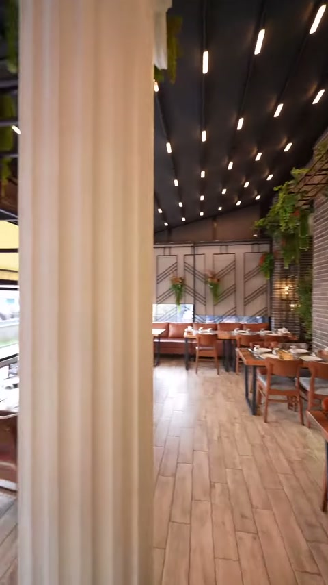 Sütun gövdesinin yivli kaplaması ve restoran oturma alanı görülüyor.