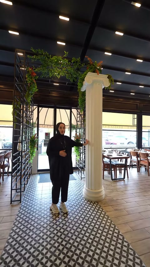 Sunucu, yivli dekoratif sütunun restoran yerleşimindeki konumunu anlatıyor.