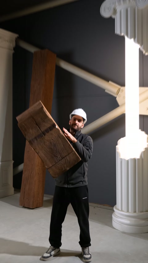 Ahşap efektli kalın kiriş parçası sergi alanında elde tutuluyor.
