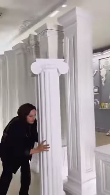İyonik başlıklı yivli sütunlar, kare kaideler üzerinde yan yana sergileniyor.