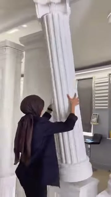 Tanıtıcı, sütun gövdesindeki derin ve paralel yivlere dokunuyor.