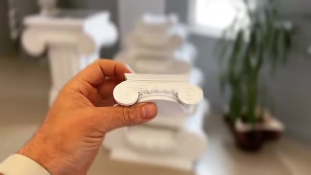 Elde tutulan minyatür İyonik sütun başlığı, iç mekân ofis ortamında