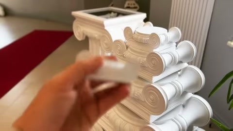 Dekoratif ek parça, yığılmış sütun başlıklarının önünde çevrilerek inceleniyor.