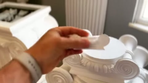 El, küçük süslemeyi başlığın üst merkezine yerleştirmeye hazırlanıyor.