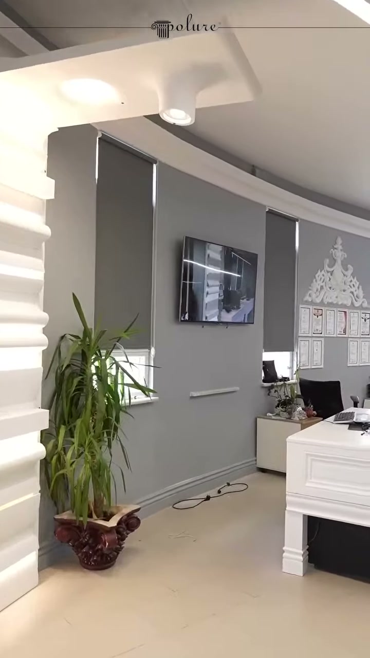 Tavandaki dekoratif konsollar ve gri duvarlı çalışma alanı görülüyor