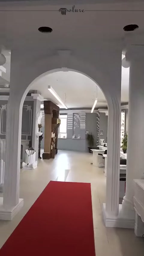 Kırmızı halılı koridorda tekrarlanan kemerli sütun düzeni sergileniyor
