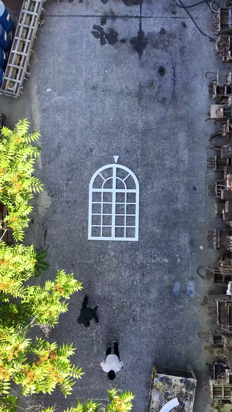 Beyaz kemerli pencere iskeleti açık atölye zemininde tek başına duruyor